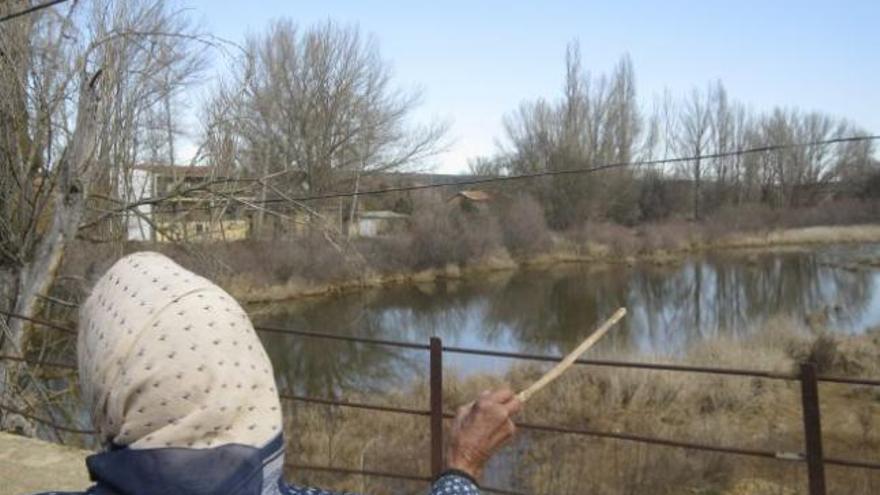 Una vecina de Villaferrueña señala ayer el bajo nivel del río Eria a su paso por la localidad.