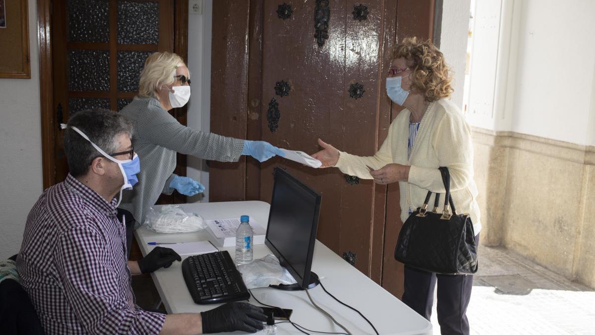 Una vecina de Ontinyent recoge una mascarilla en el edificio del antiguo consistorio