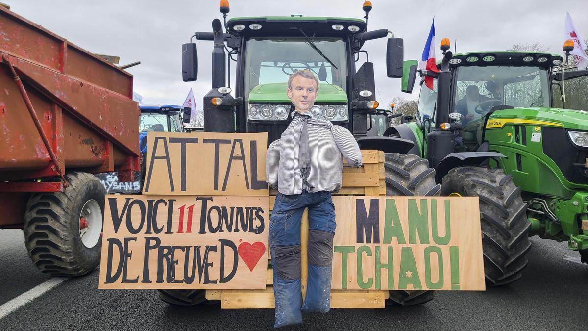 Un agricultor francés lleva en su tractor carteles protesta y un muñeco de Macron.