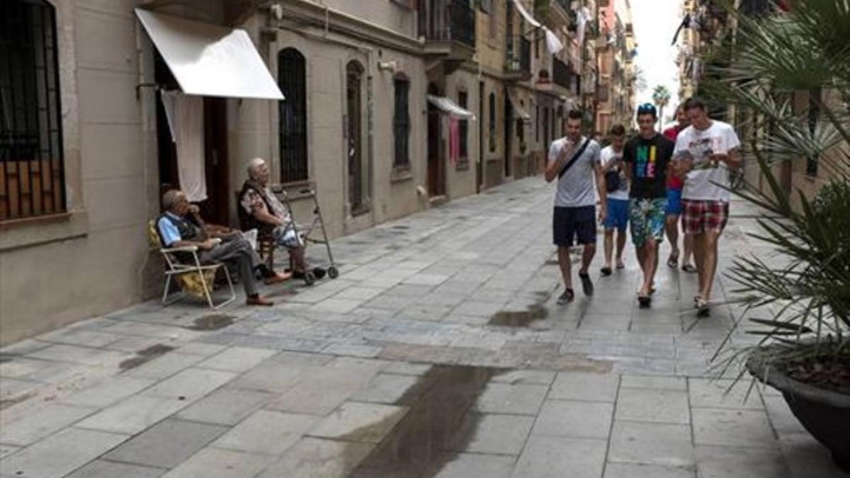 Dos vecinos tomando la fresca en la calle, símbolo del barrio, observan pasar a un grupo de turistas.