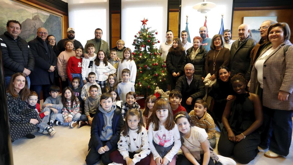 Los alumnos del Colegio Público Carmen Ruiz Tilve, junto a un grupo de influencers y miembros de la Federación de Asociación de Mayores del Principado de Asturias posan junto al árbol que tiene Barbón en su despacho.