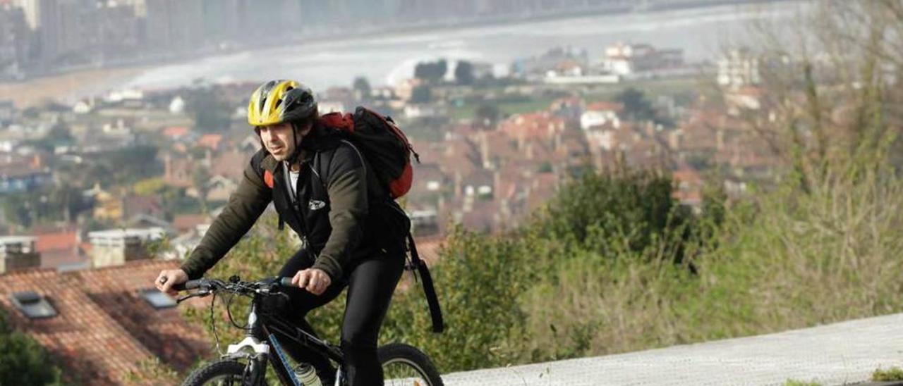 Un cicloturista, con la bahía de Gijón al fondo