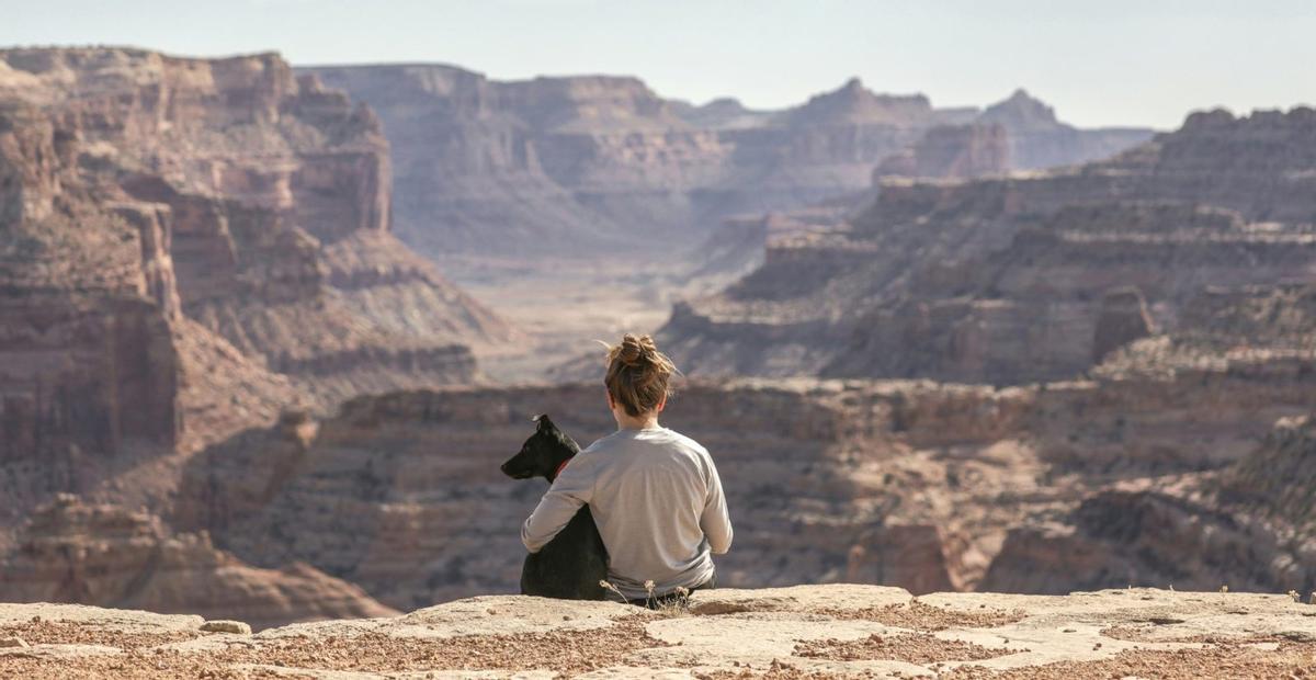 Una turista amb el seu gos davant la immensitat d’un paisatge muntanyós.  | EUROPA PRESS