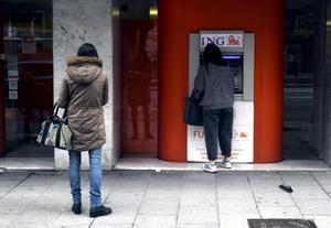 Una mujer espera su turno frente a un cajero.