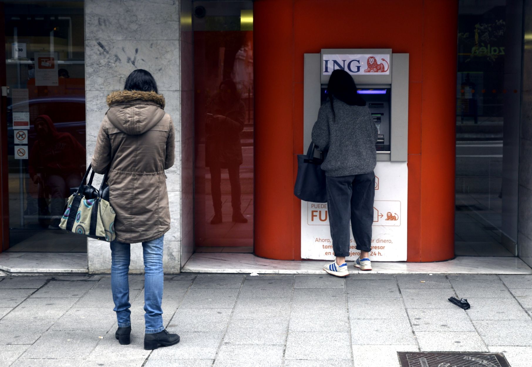 Una mujer espera su turno frente a un cajero de ING.