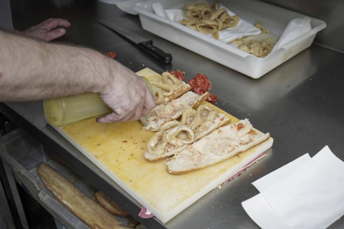 El cuiner posa oli al pa dels entrepans de calamars