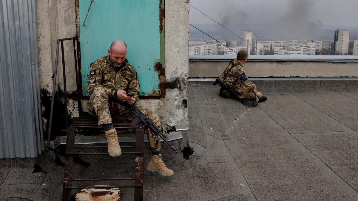 Ukrainian soldiers sit on a roof as a northern residential district in Kharkiv is shelled from Russian positions in as Russia's attack on Ukraine continues