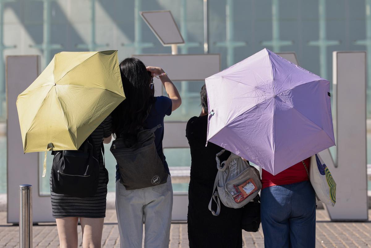 Turistas hoy en València armados con paraguas para protegerse del sol.