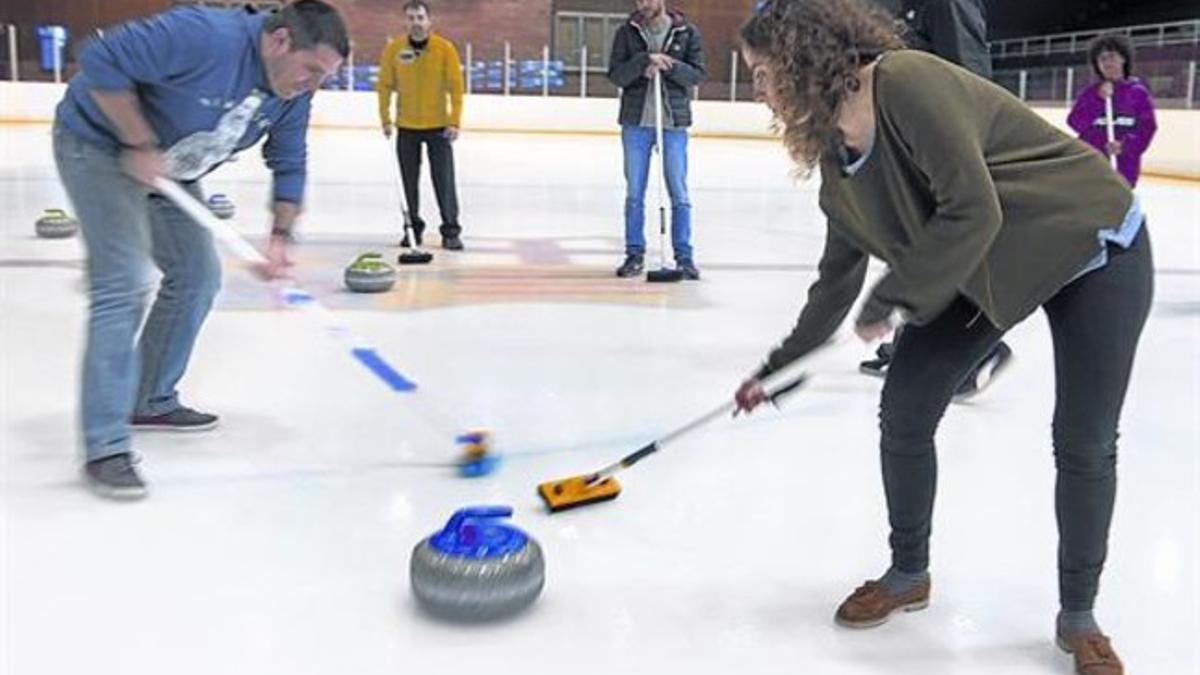 Dos de los alumnos de la 'masterclass' de Navarro, el pasado lunes, frotan el suelo ante una de las míticas piedras de curling.