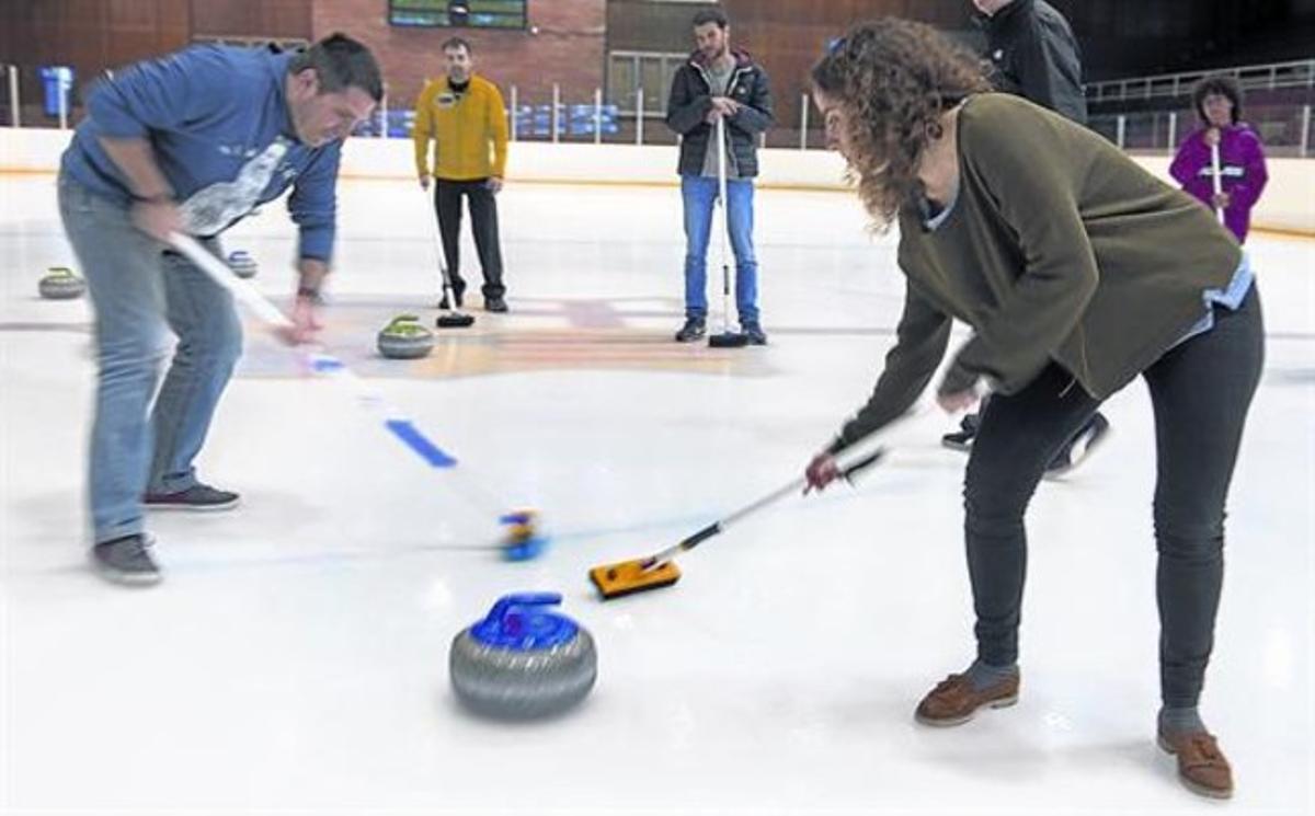 Dos dels alumnes de la ’masterclass’ de Navarro, dilluns passat, freguen el terra davant una de les mítiques pedres de cúrling.