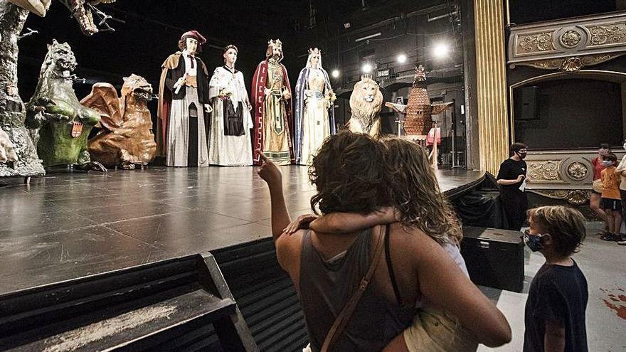 Una família observant l&#039;escenari del teatre Conservatori, on hi ha els gegants i altres figures de la imatgeria