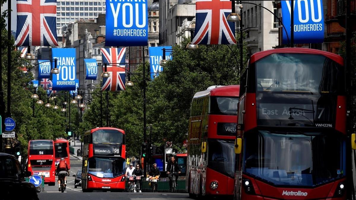 Autobuses pasan bajo banderas de la 'Union Jack' y banderolas con mensajes a los &quot;héroes&quot; del coronavirus en Oxford Street.