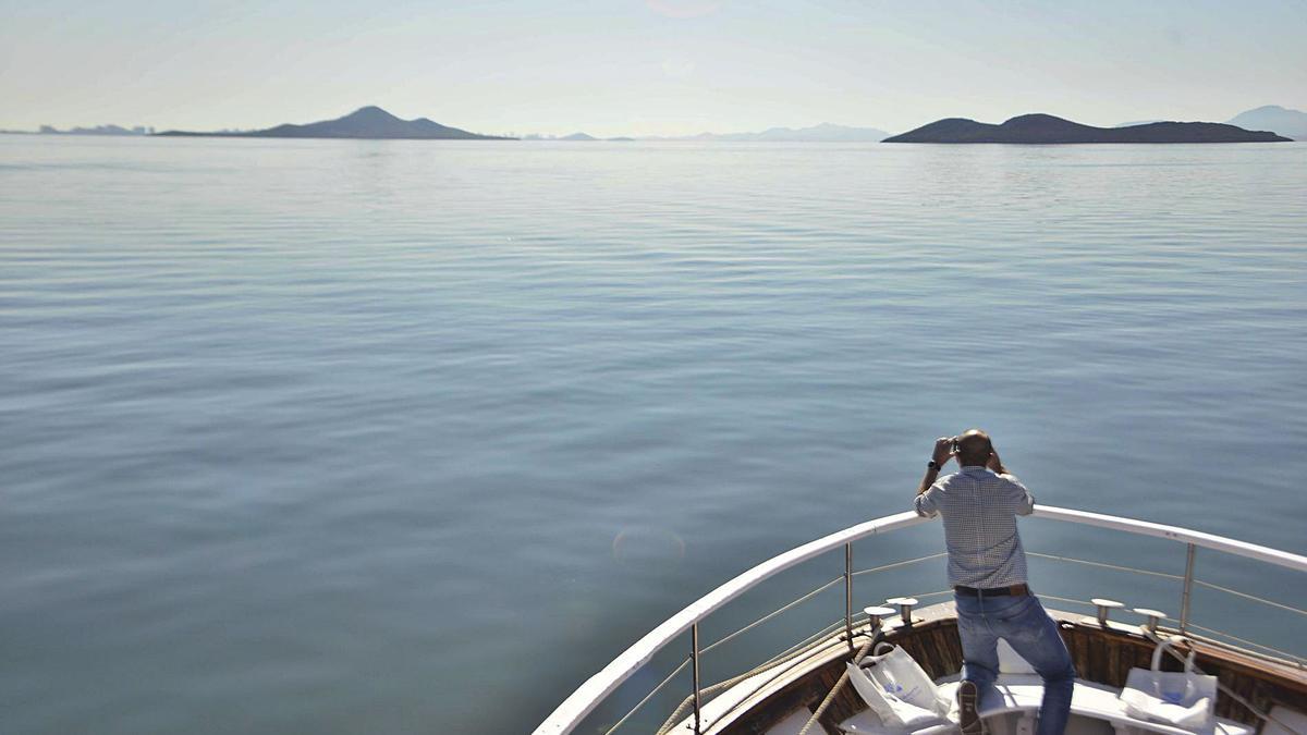 Un hombre contempla desde un barco el Mar Menor, en calma