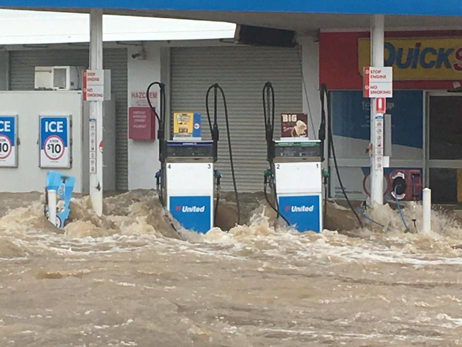 Waves crash against pumps at flooded gas station ...