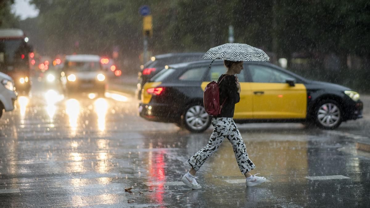 Una chica camina bajo el paraguas y la lluvia.