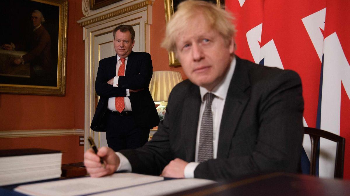 El primer ministro británico, Boris Johnson, en el momento de firmar el acuerdo con la UE  ante la mirada de David Frost.