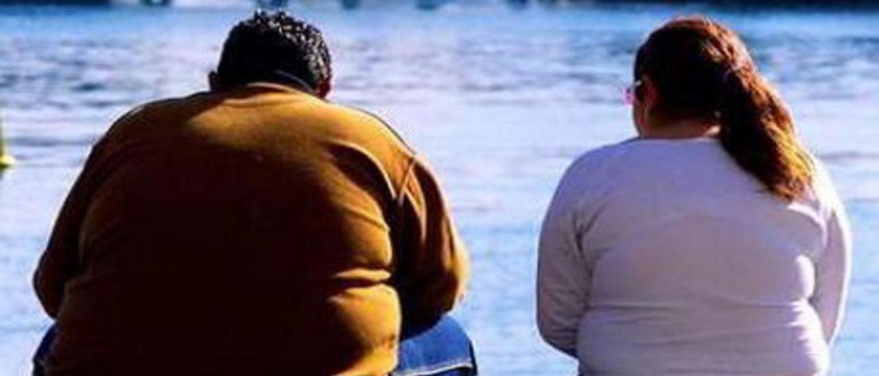 Una pareja con obesidad, conversando frente al mar.