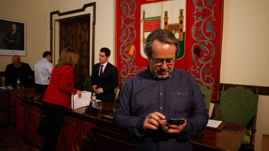Guarido lee su móvil al término de un Pleno, con Fagúndez al fondo.