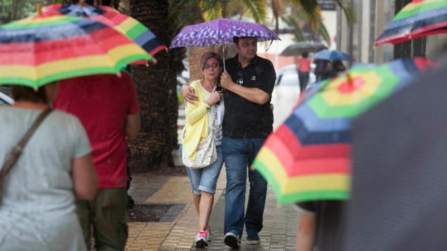 Varias personas se protegen de la lluvia en Santa Cruz de Tenerife.