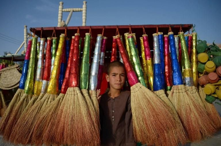 Rafi, de 9 años, vende escobas en un puesto al borde de la carretera en Mazar-i-Sharif/ AFP PHOTO / Farshad USYAN