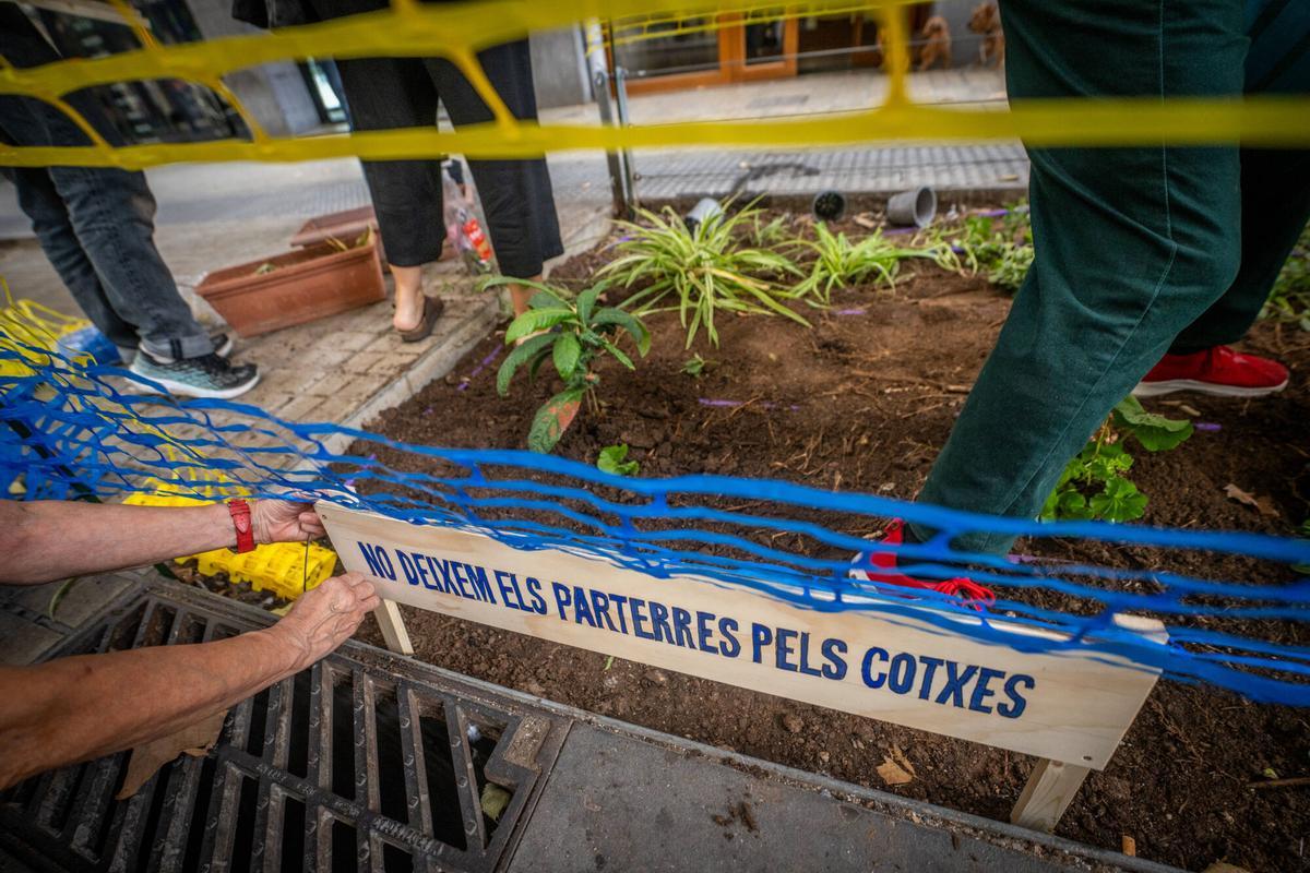 Un vecino coloca un cartel reivindicativo en los parterres.