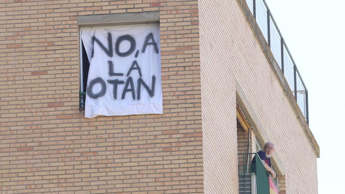 Un vecino de Huesca cuelga una pancarta contraria a la OTAN.