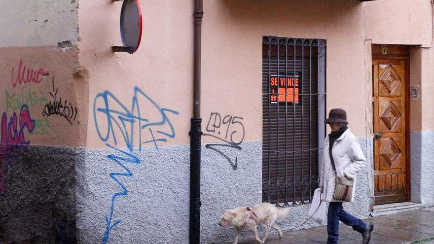 Una mujer pasa frente a un piso en venta.