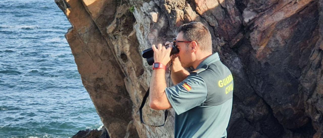 Un agente de la Guardia Civil rastrea el mar desde el acantilado. | Guardia Civil.