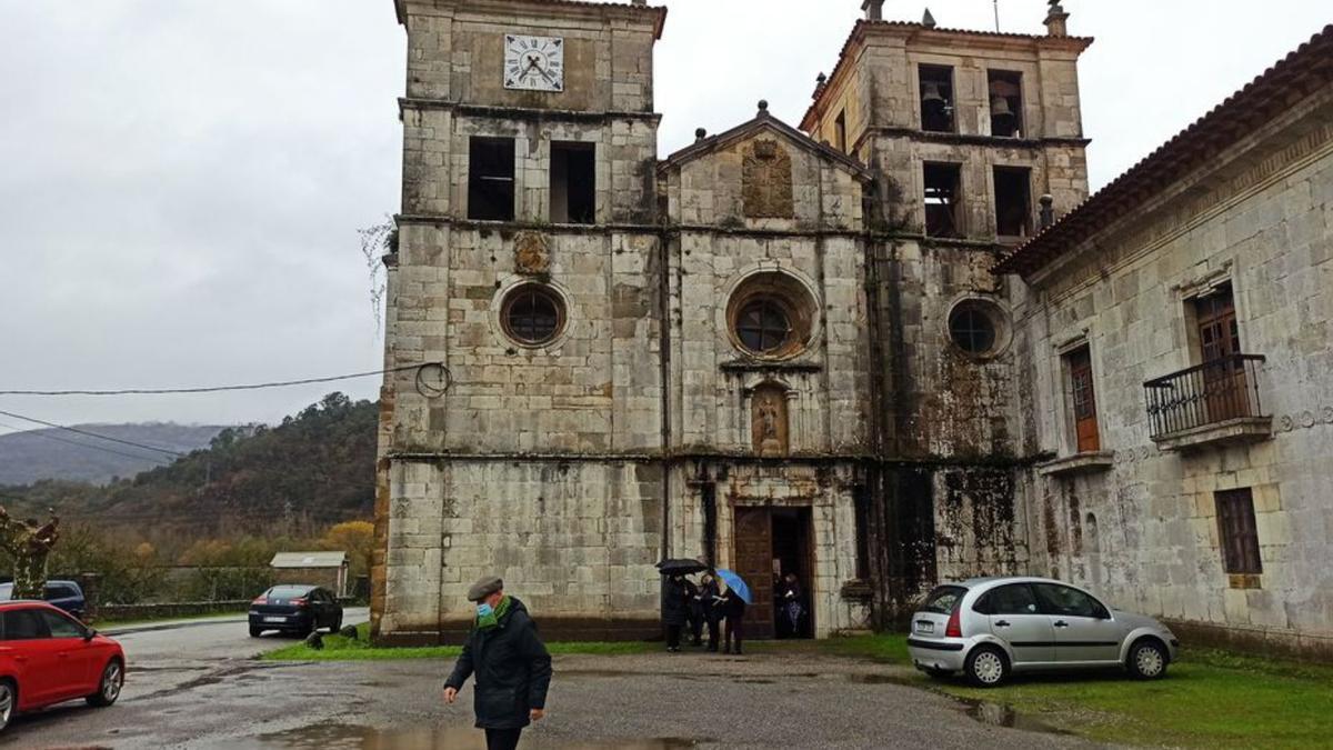 Varios vecinos, ayer, a la salida de la misa dominical en la iglesia del monasterio, cuya fachada está afectada por la humedad. | S. Arias