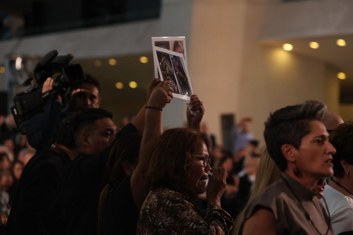 Familiars de les víctimes de la dana mostren a les autoritats polítiques retrats dels seus estimats al funeral d'Estat, al Museu de les Ciències de València.