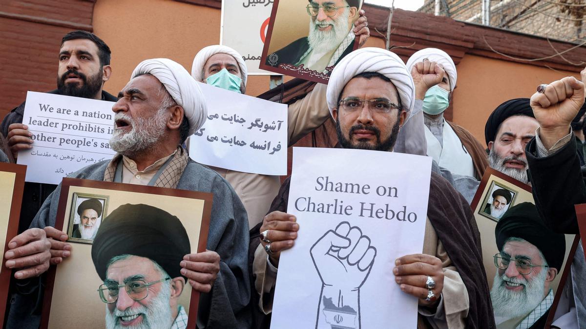 Demonstrators gather with images of Iran's supreme leader Ayatollah Ali Khamenei during a protest against defamatory cartoons depicting him published by French satirical weekly Charlie Hebdo, outside the French embassy in Iran's capital Tehran on January 8, 2023. (Photo by ATTA KENARE / AFP)