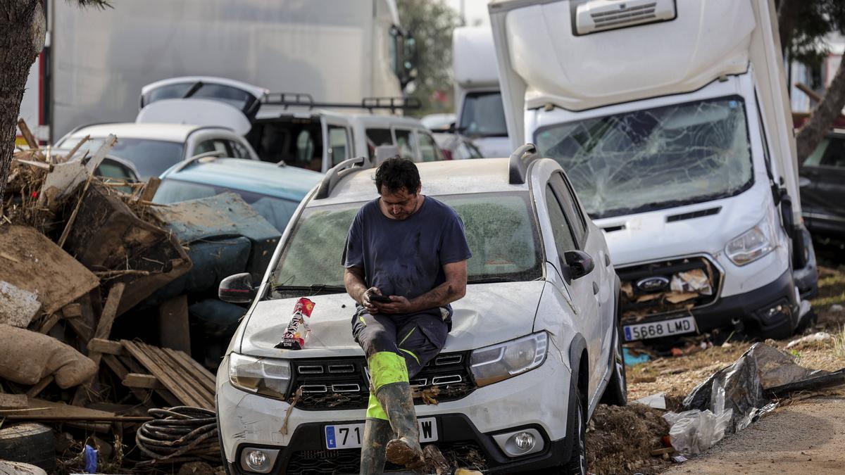 Un hombre consulta el móvil apoyado sobre su coche en la autopista de Silla. LLUVIAS. GOTA FRIA. DANA. RIADA. INUNDACIONES