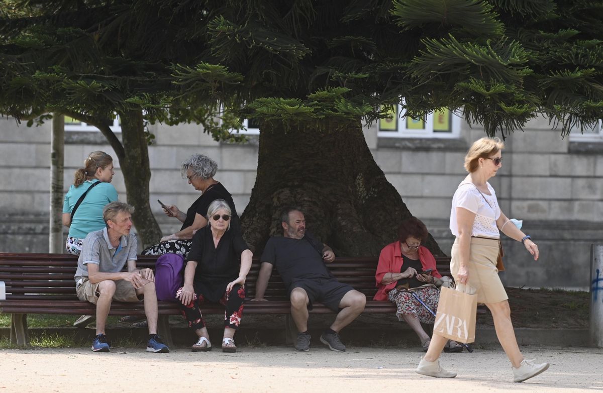 Varias personas se refugian del calor a la sombra de un árbol ayer en Pontevedra.