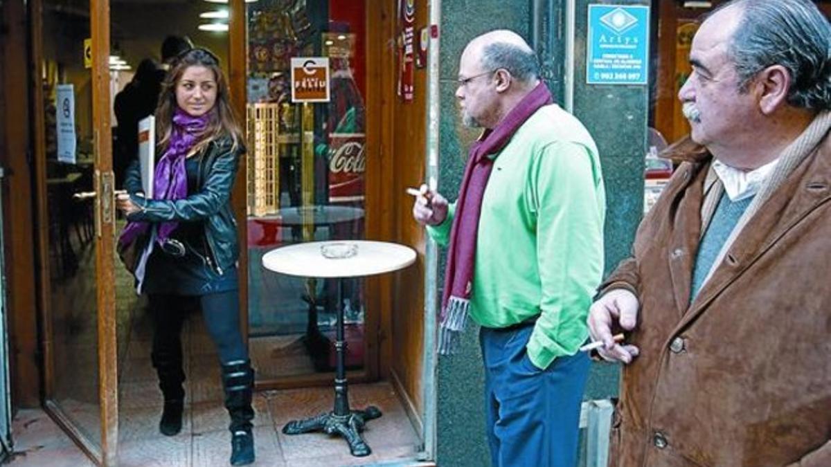 En la calle 8 La inspectora Montse del Campo saluda a dos fumadores, apostados ante la puerta del bar El Café, de Sant Feliu de Llobregat, ayer.