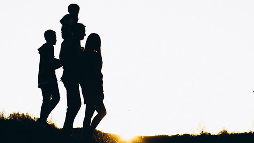 Una familia pasea por el litoral durante la puesta de sol.