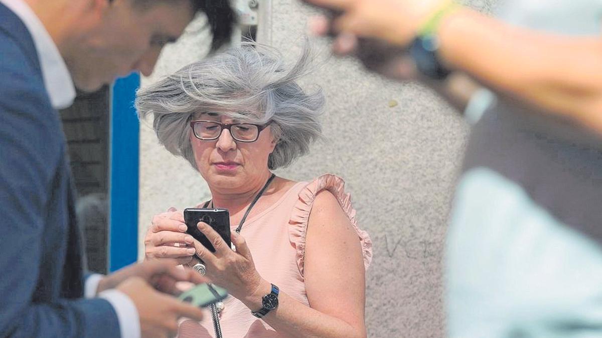 Varios ciudadanos consultan el móvil en la calle.