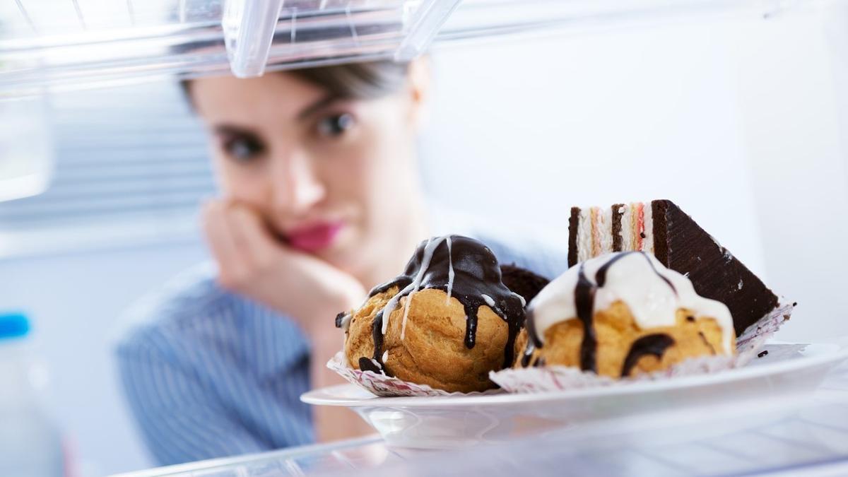 Una mujer mira unos dulces en una nevera.