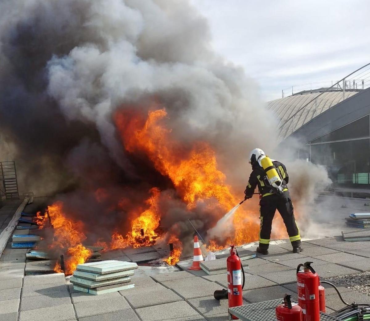 Un bombero de Alicante acomete las llamas localizadas sobre un tejado del aeropuerto, en un accidente real