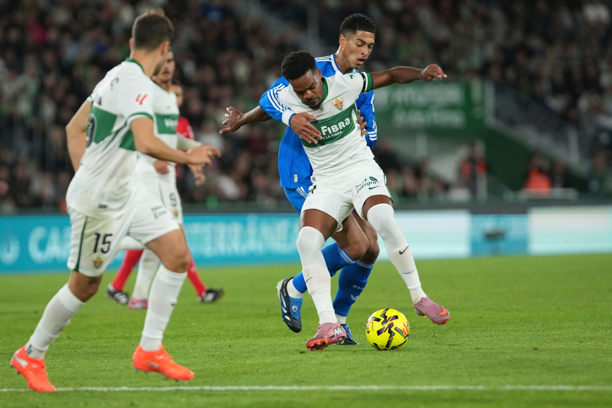 Real Madrid's Jude Bellingham, right background, and Elche's Mourad challenge for the ball during the Spanish La Liga soccer match between Elche and Real Madrid in Elche, Spain, Sunday, Nov. 23, 2025. (AP Photo/Alberto Saiz)