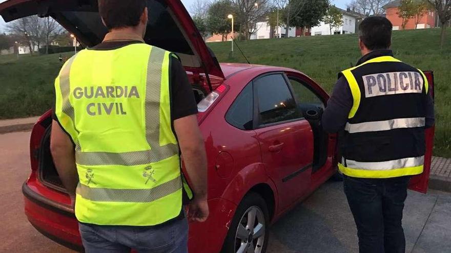 Agentes de la Guardia Civil y la Policía Nacional junto a uno de los vehículos incautados. // OPC Pontevedra