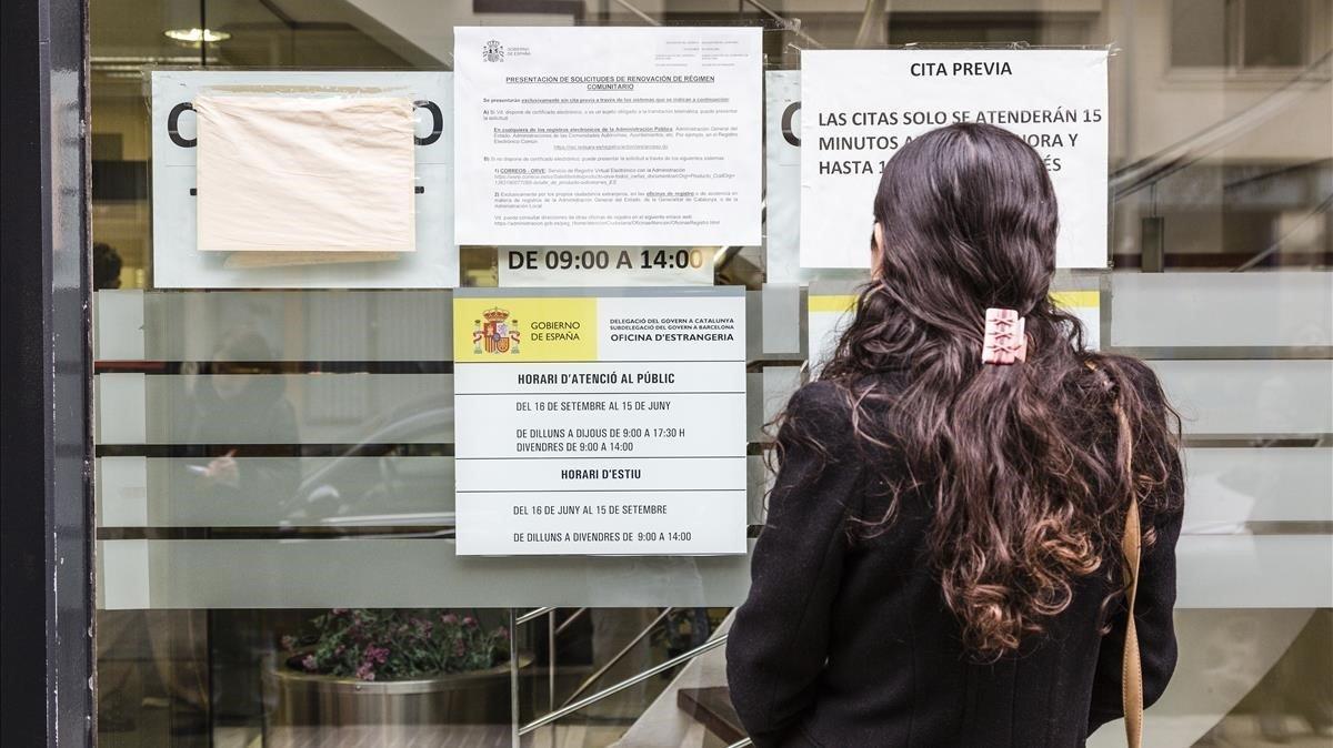 Una mujer consulta los papeles enganchados en una oficina de extranjería en Barcelona.