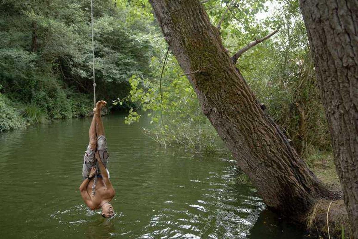 Un joven se columpia en el río Mero a su paso por Cecebre. juan varela