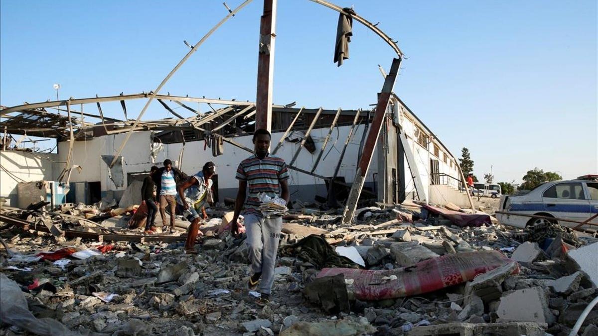 Inmigrantes recogen lo que queda de sus pertenencias tras el ataque aéreo sufrido en Trípoli