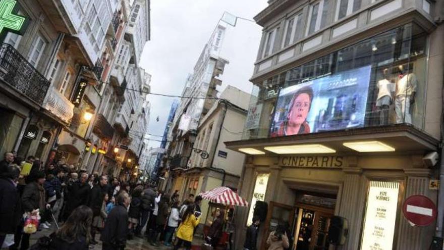 Peatones en la calle Real siguen la película &#039;Regreso al futuro&#039;, ayer, en el antiguo cine París. / fran martínez