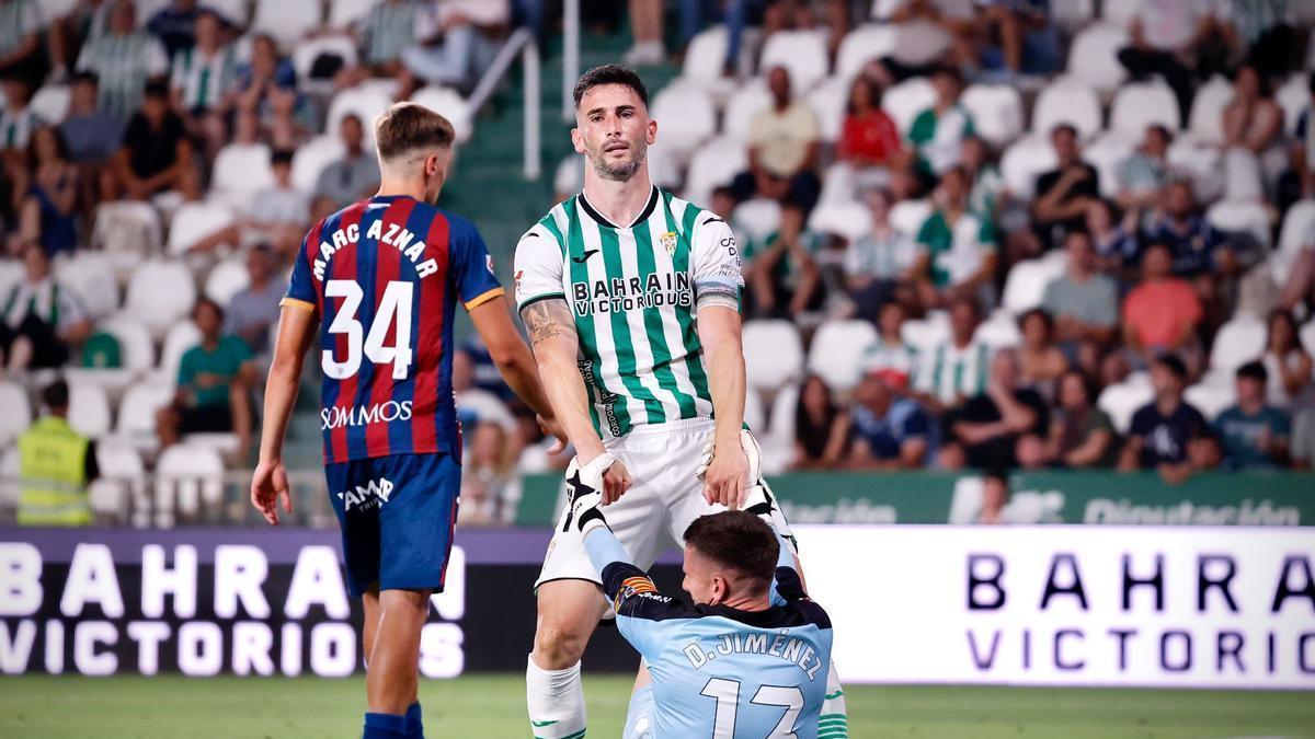 Carlos Albarrán ayuda a levantarse a Dani Jiménez, meta del Huesca, en el choque en El Arcángel.