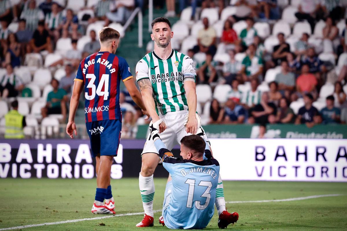 Carlos Albarrán ayuda a levantarse a Dani Jiménez, meta del Huesca, en el choque en El Arcángel.