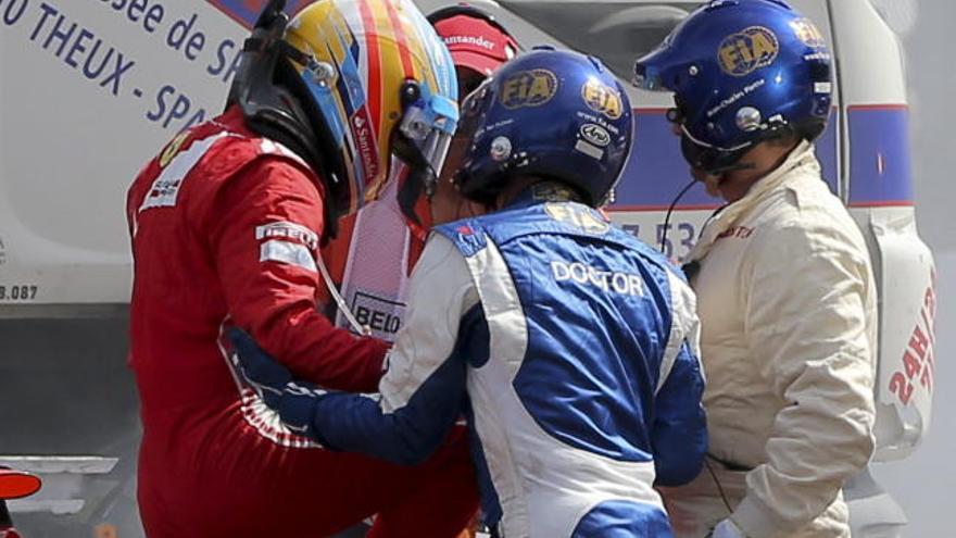 Alonso sale de su monoplaza tras el accidente ayudado por dos operarios.