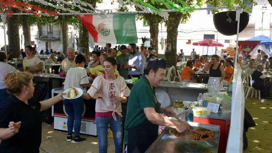 Arriba, unos de los visitantes de la fiesta prueban uno de los platos típicos. A la derecha uno de los puestos de comida mejicana. // Gustavo Santos