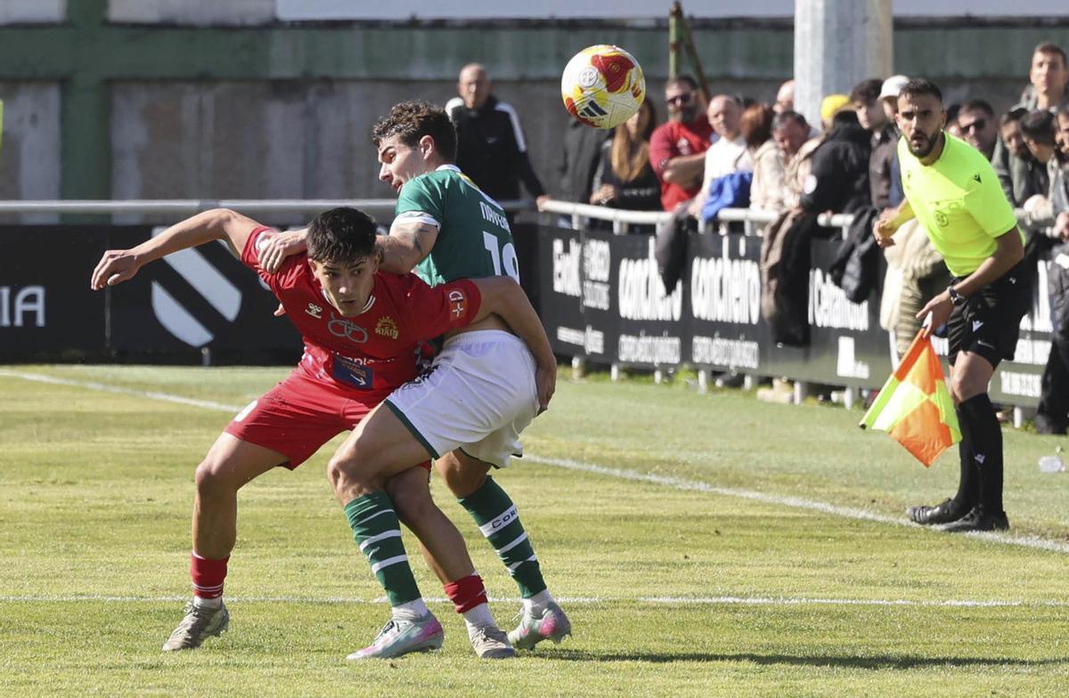 Naveira, del Coruxo, lucha con un jugador rival por hacerse con el control del balón. | ALBA VILLAR