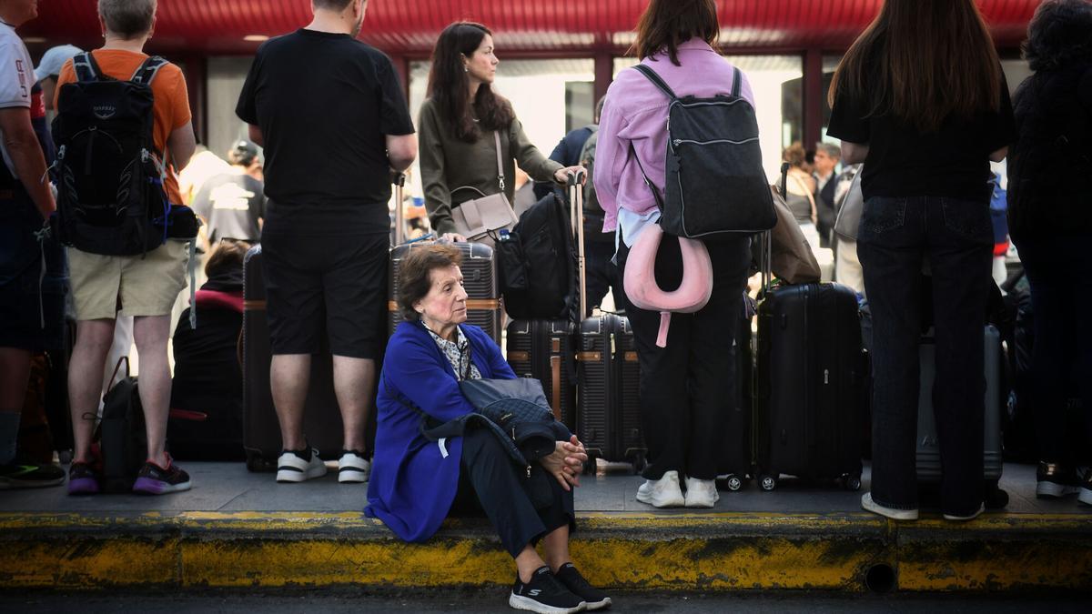 Viajeros en la estación de trenes de Madrid Puerta de Atocha esperan noticias sobre el apagón que paralizó la red ferroviaria.